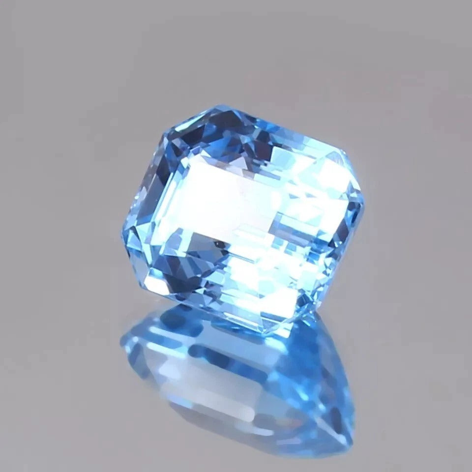 Faceted blue sapphire gemstone on a gray background