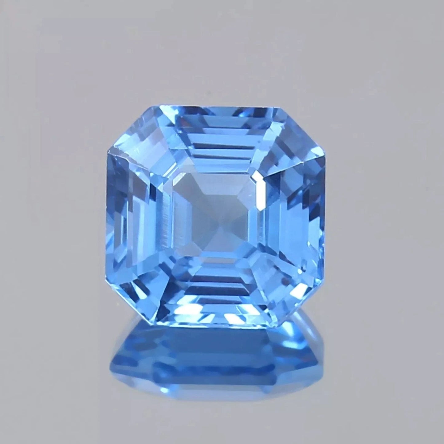 Faceted Ceylon Blue Sapphire gemstone on a gray background