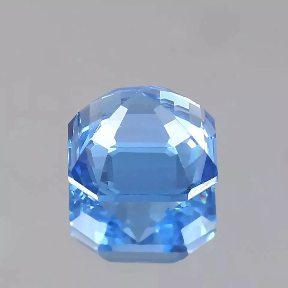Faceted Ceylon Blue Sapphire gemstone on a gray background