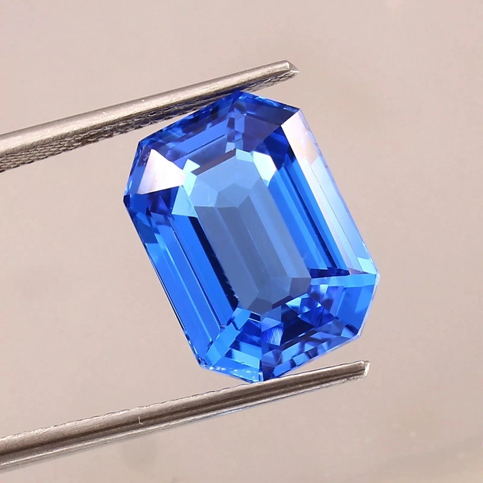 Blue sapphire sri lanka gemstone held by tweezers on a neutral background