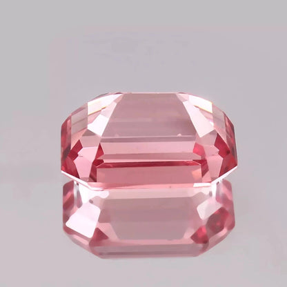 Faceted Padparadscha Sapphire Peach to Pink gemstone on a gray background