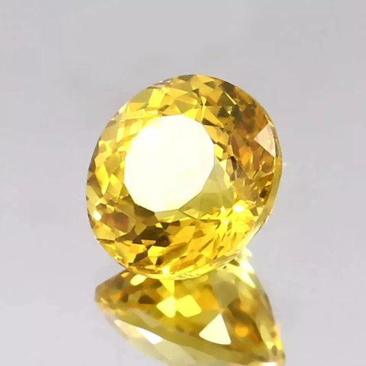 Close-up of a Ceylon Yellow Sapphire gemstone on a light gray background