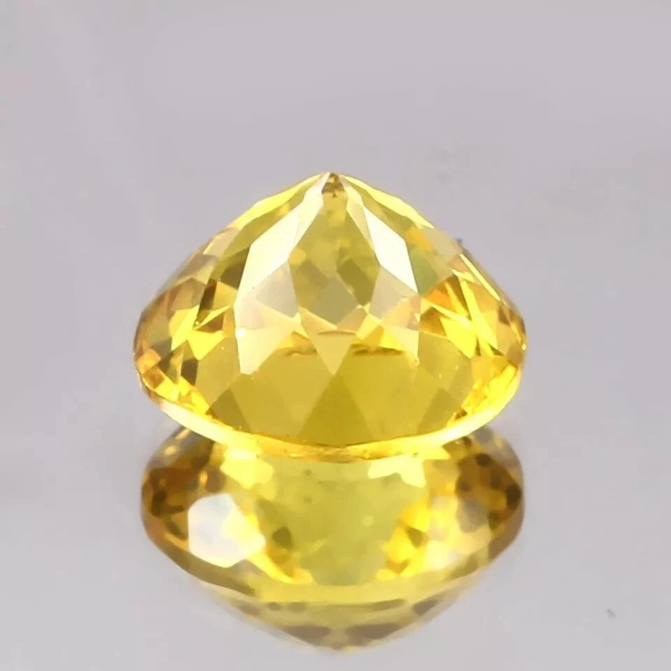 Faceted Ceylon Yellow Sapphire gemstone on a gray background