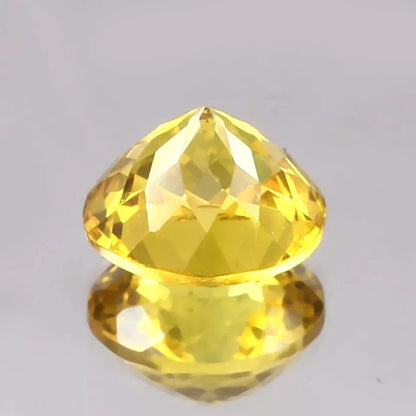 Faceted Ceylon Yellow Sapphire gemstone on a gray background