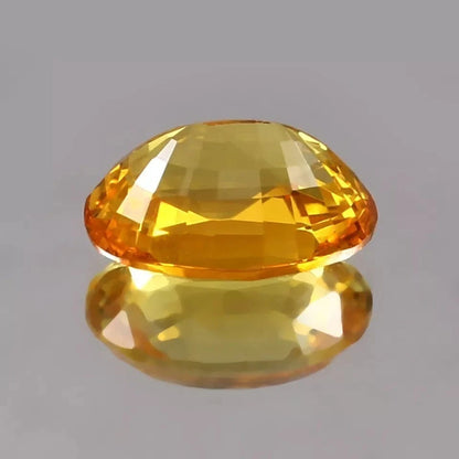 Yellow Sapphire gemstone on a reflective gray surface