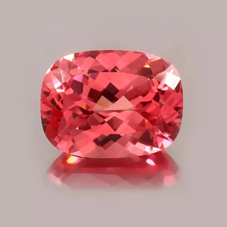Cushion-shaped Padparadscha Sapphire gemstone on a gray background